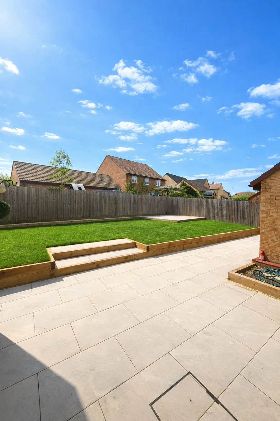 Raised sandstone patio area with steps leading to a lawn