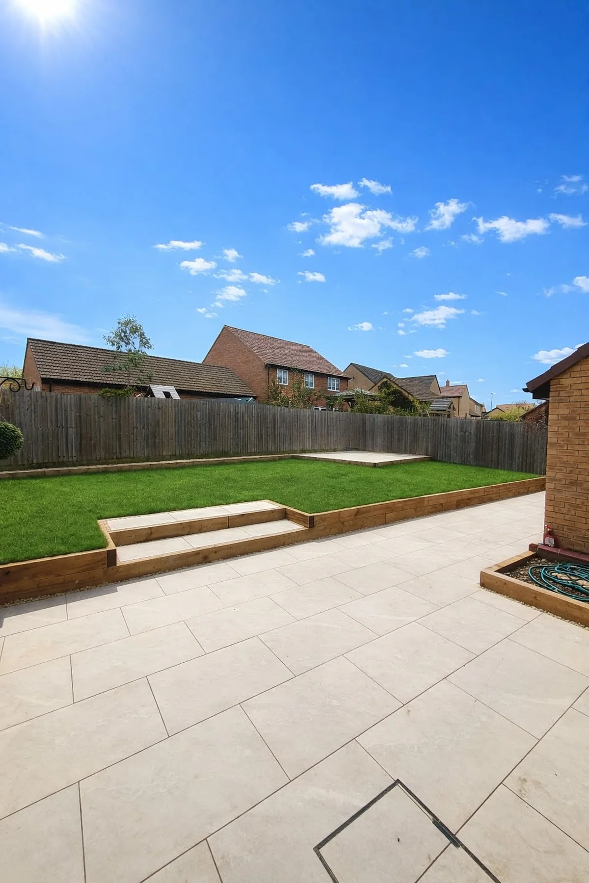 Completed sandstone patio with steps, lawn and timber fencing